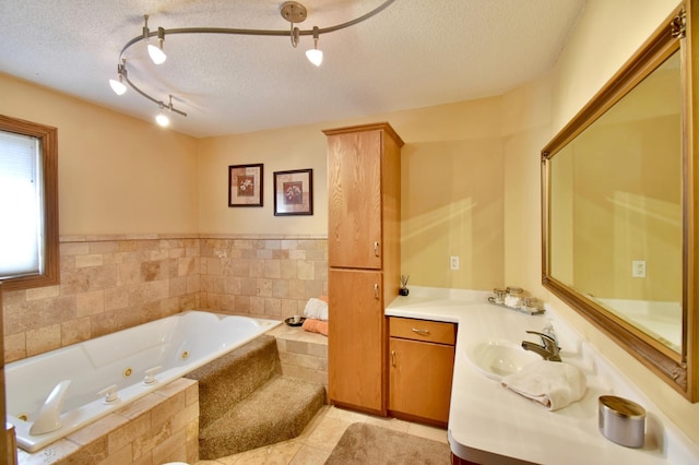 bathroom featuring tile patterned floors, a textured ceiling, a tub with jets, and vanity