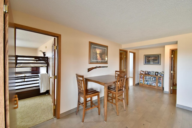 dining space with a textured ceiling, baseboards, and wood finished floors