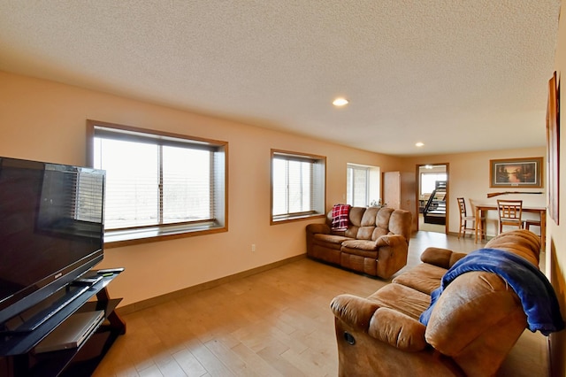 living room with recessed lighting, a textured ceiling, baseboards, and wood finished floors