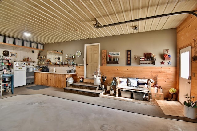 garage with wooden walls, a workshop area, and freestanding refrigerator