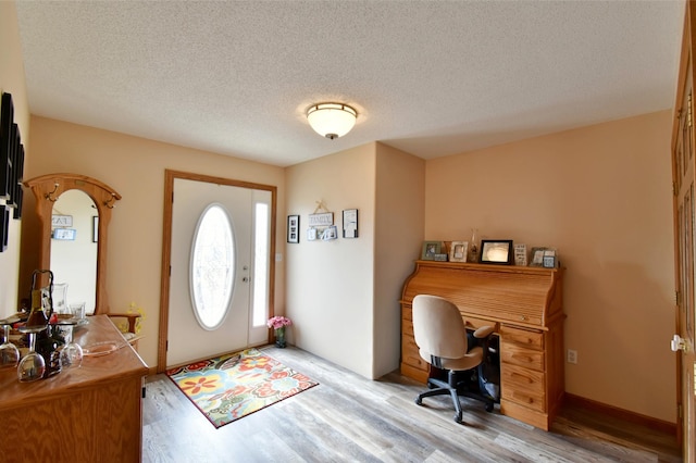 entrance foyer featuring light wood-style flooring, baseboards, and a textured ceiling