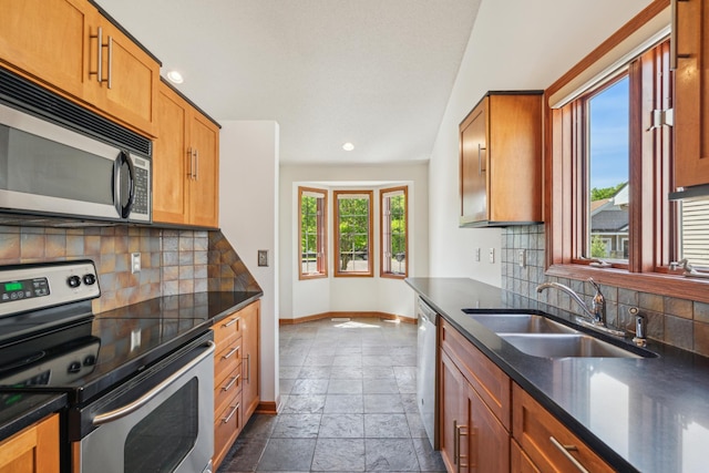 15436 70th Ave N, Maple Grove, MN 55311 - kitchen with stainless steel appliances, baseboards, stone tile floors, a sink, and dark countertops