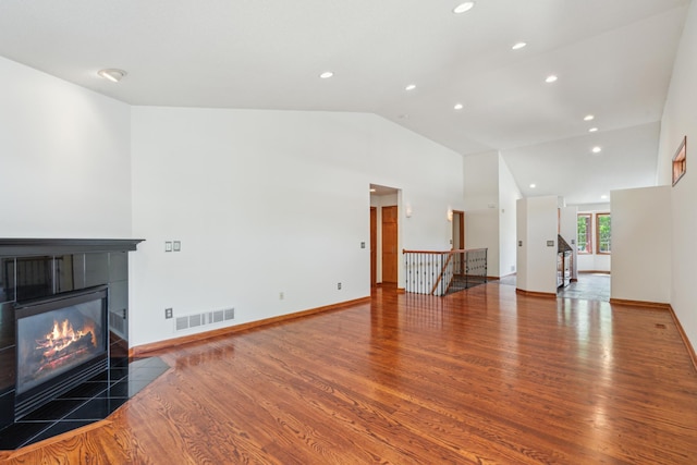 15436 70th Ave N, Maple Grove, MN 55311 - unfurnished living room featuring vaulted ceiling, a tiled fireplace, wood finished floors, recessed lighting, and baseboards