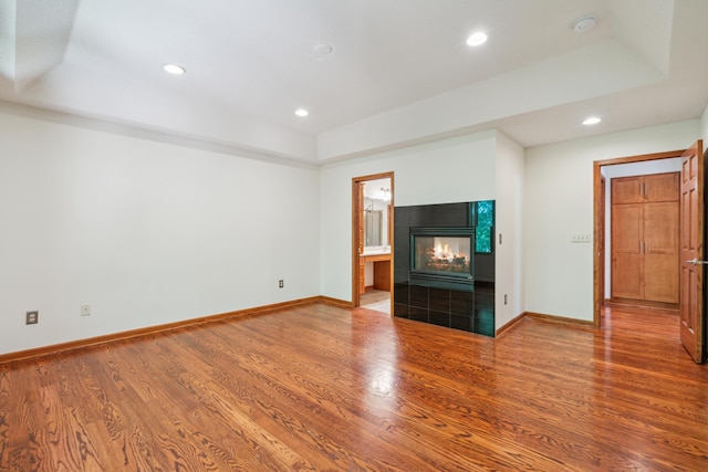 15436 70th Ave N, Maple Grove, MN 55311 - unfurnished living room with a tray ceiling, a tiled fireplace, wood finished floors, baseboards, and recessed lighting
