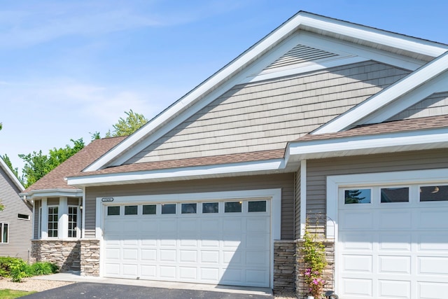 15436 70th Ave N, Maple Grove, MN 55311 - view of front of house featuring stone siding, a shingled roof, driveway, and a garage