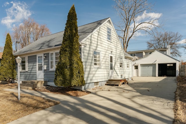 view of side of home featuring an outdoor structure, a detached garage, and a shingled roof