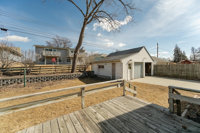 wooden deck with a garage, an outbuilding, and fence