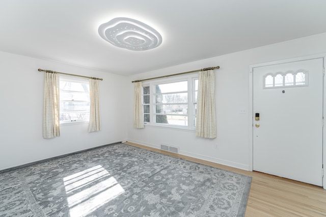 foyer entrance featuring visible vents, baseboards, and light wood-style flooring