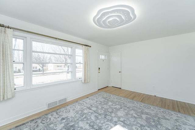 empty room featuring wood finished floors, visible vents, and baseboards