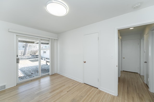 unfurnished bedroom with access to outside, light wood-style flooring, and visible vents