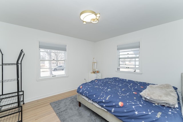 bedroom featuring multiple windows, baseboards, and wood finished floors