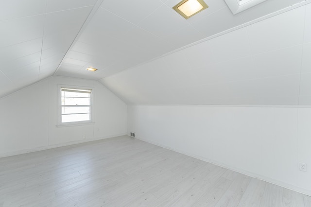 bonus room with light wood finished floors, visible vents, and vaulted ceiling