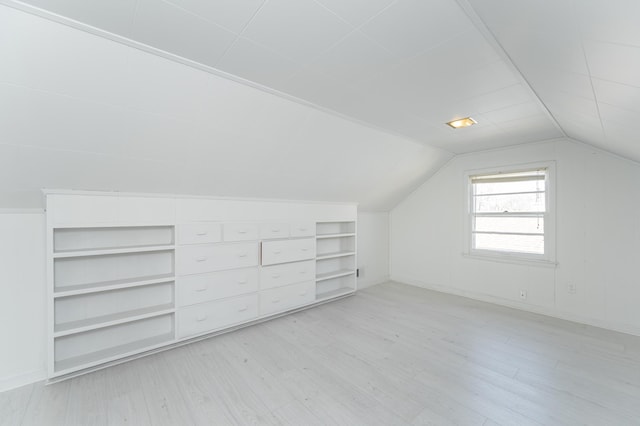 additional living space featuring light wood finished floors, built in shelves, and vaulted ceiling