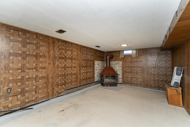 below grade area featuring wooden walls, visible vents, and a wood stove