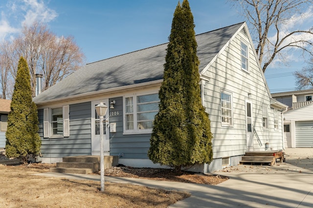 view of front facade featuring concrete driveway, a garage, and roof with shingles