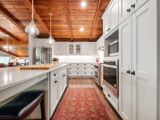 2904 Le Homme Dieu Vw NE, Alexandria, MN 56308 - kitchen with wood ceiling with exposed beams, stainless steel appliances, light countertops, hanging light fixtures, and light wood-type flooring