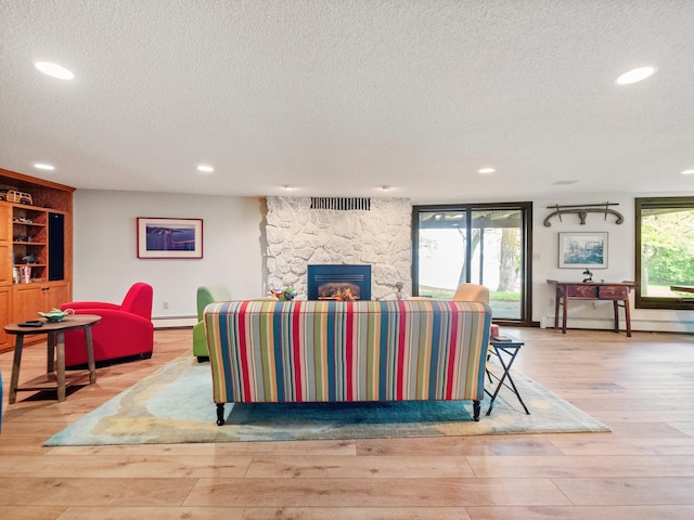 2904 Le Homme Dieu Vw NE, Alexandria, MN 56308 - living room featuring a textured ceiling, a baseboard radiator, light wood-type flooring, a stone fireplace, and recessed lighting