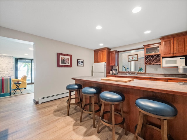 2904 Le Homme Dieu Vw NE, Alexandria, MN 56308 - kitchen with a baseboard radiator, white appliances, a breakfast bar, brown cabinetry, and light wood-type flooring