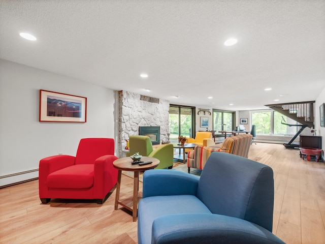 2904 Le Homme Dieu Vw NE, Alexandria, MN 56308 - living room with a baseboard heating unit, light wood-style floors, a stone fireplace, recessed lighting, and a textured ceiling