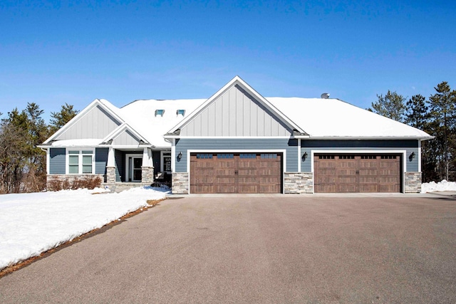 craftsman inspired home featuring board and batten siding, stone siding, and aphalt driveway