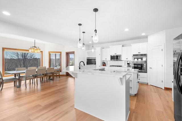 1502 Epperstone Enclave, Byron, MN 55920 - kitchen featuring appliances with stainless steel finishes, a spacious island, recessed lighting, light wood-style flooring, and white cabinetry