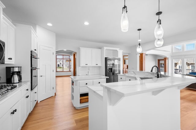 1502 Epperstone Enclave, Byron, MN 55920 - kitchen featuring arched walkways, stainless steel appliances, a spacious island, light wood-style flooring, and recessed lighting