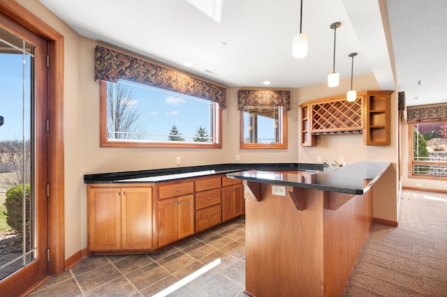1502 Epperstone Enclave, Byron, MN 55920 - kitchen featuring open shelves, dark countertops, a kitchen breakfast bar, hanging light fixtures, and brown cabinets