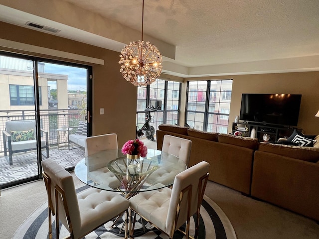 carpeted dining area featuring visible vents, a chandelier, and a textured ceiling