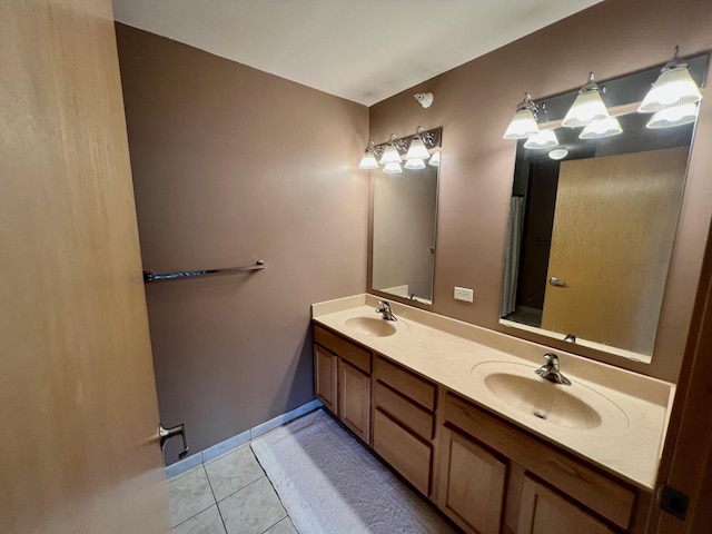 bathroom featuring double vanity, a sink, baseboards, and tile patterned floors