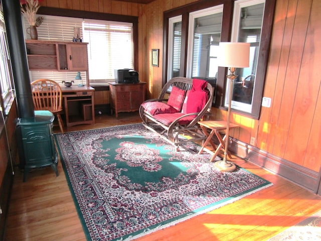 interior space featuring a wood stove, wooden walls, and wood finished floors