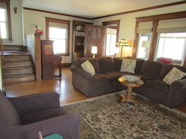 living area with ornamental molding, stairs, baseboards, and wood finished floors