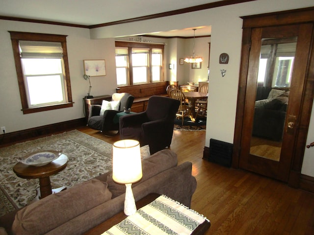 living area featuring ornamental molding, wood finished floors, a wealth of natural light, and an inviting chandelier