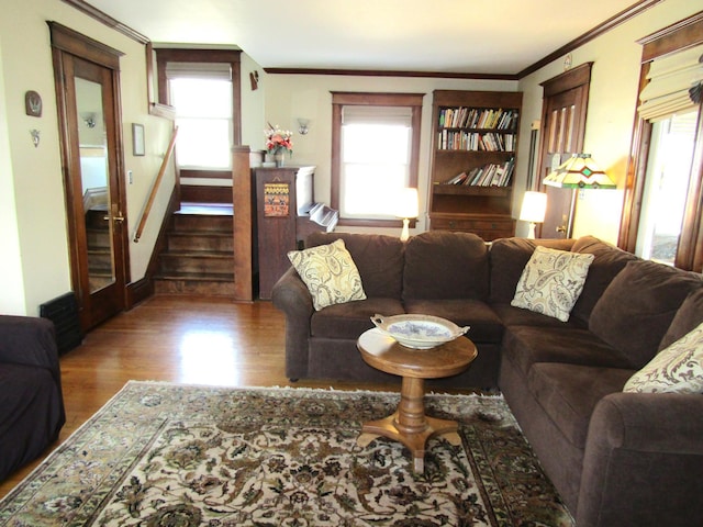 living area with crown molding, stairs, and wood finished floors