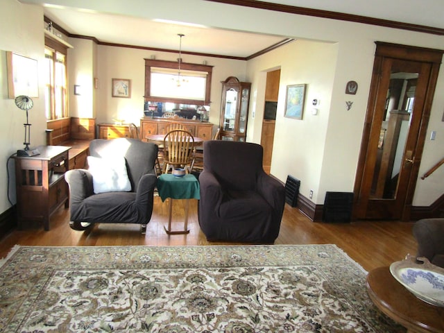 living room featuring baseboards, wood finished floors, and crown molding