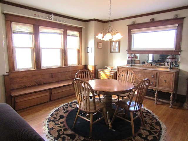 dining area featuring light wood-style floors, ornamental molding, and an inviting chandelier