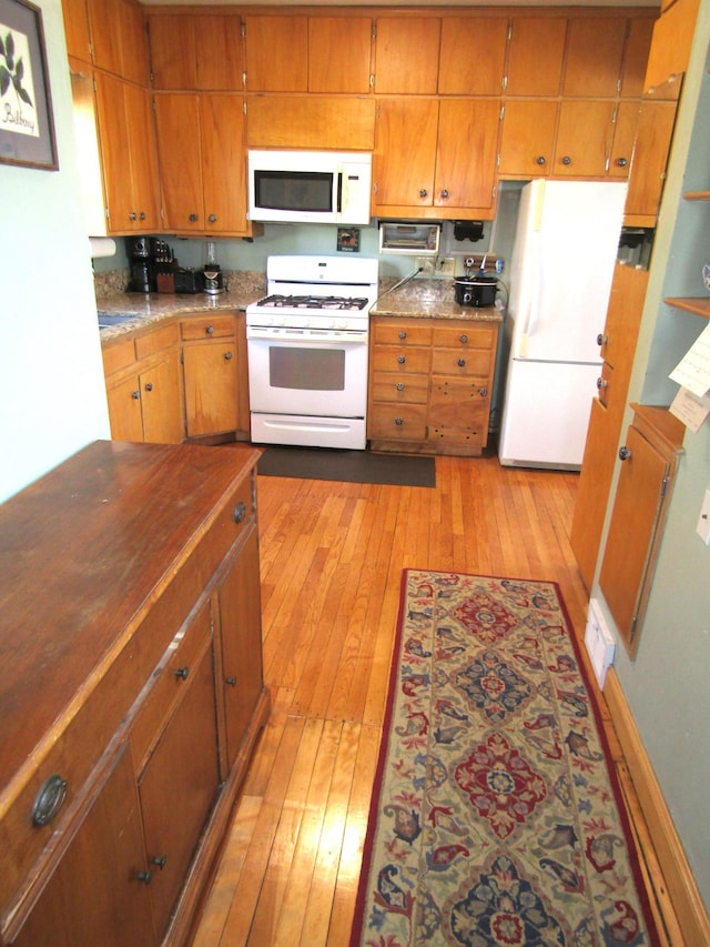 kitchen with light countertops, white appliances, light wood-type flooring, and brown cabinets