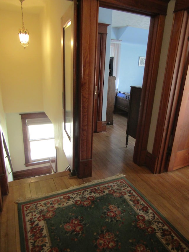 corridor with hardwood / wood-style floors and an inviting chandelier