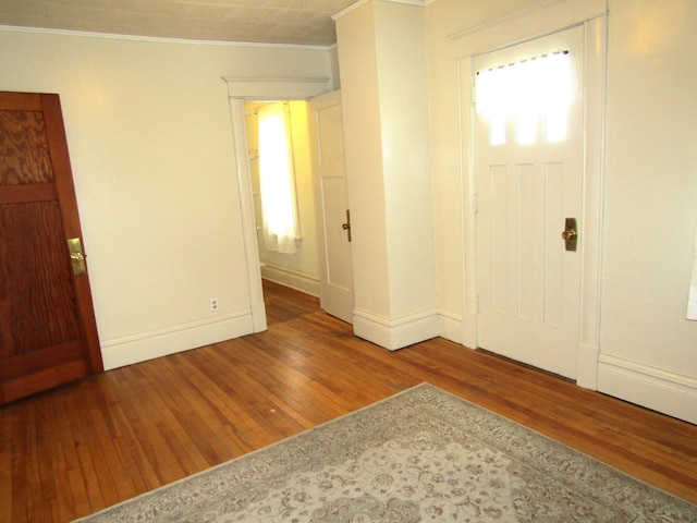 entrance foyer with ornamental molding, baseboards, and wood finished floors