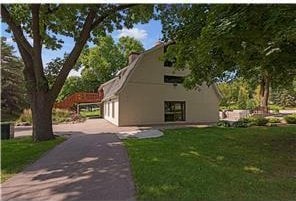 exterior space with aphalt driveway, a gambrel roof, a lawn, and a garage