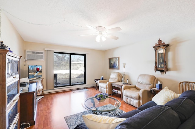 living area with ceiling fan, a wall unit AC, wood finished floors, and a textured ceiling