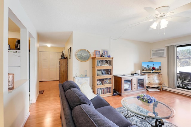 living area with light wood finished floors, visible vents, baseboards, an AC wall unit, and a ceiling fan