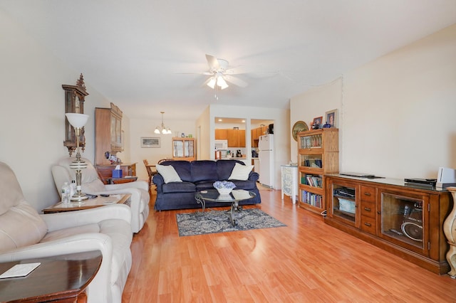 living room with light wood-style flooring and ceiling fan with notable chandelier