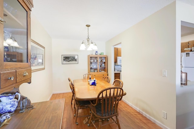 dining area featuring a notable chandelier, light wood-style flooring, and baseboards