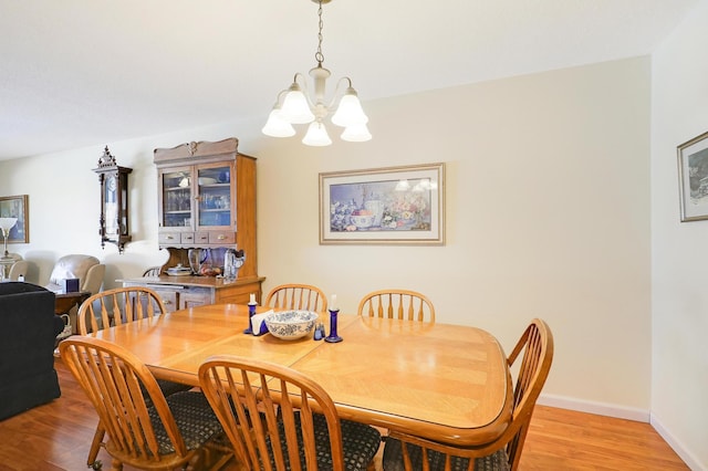 dining space featuring an inviting chandelier, light wood-type flooring, and baseboards