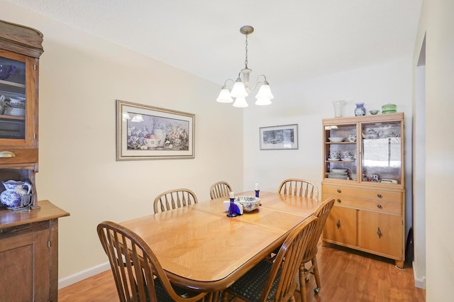 dining room featuring baseboards, an inviting chandelier, and light wood finished floors