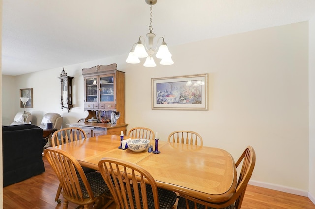 dining room featuring a notable chandelier, baseboards, and light wood-type flooring