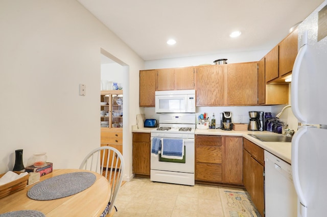 kitchen featuring a sink, recessed lighting, white appliances, brown cabinetry, and light countertops