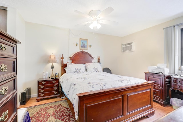 bedroom featuring an AC wall unit, light wood finished floors, and ceiling fan