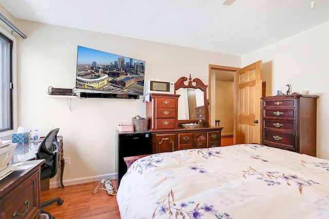 bedroom with baseboards, a textured ceiling, and wood finished floors