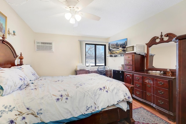 bedroom featuring a wall mounted air conditioner, a ceiling fan, and wood finished floors